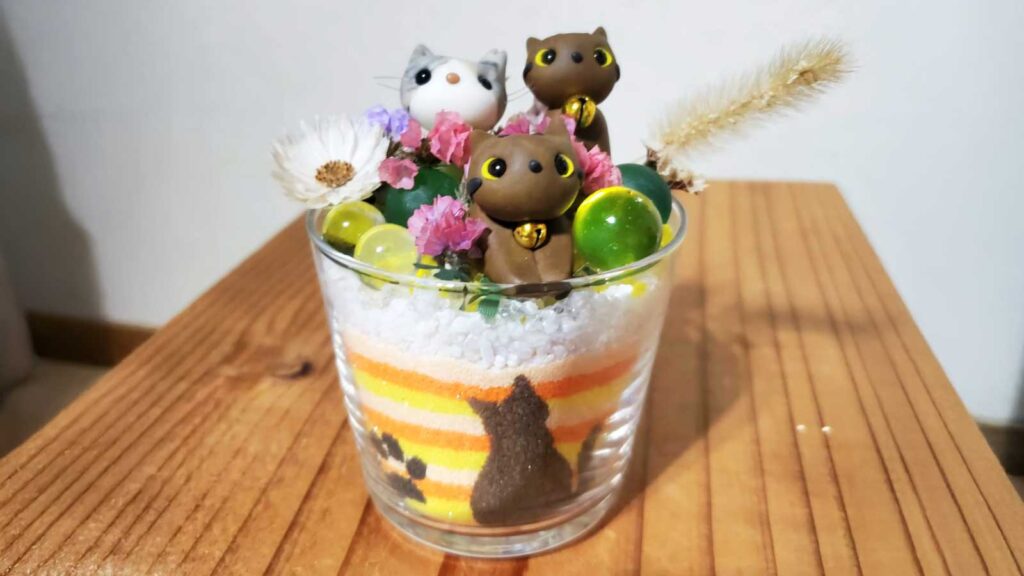かわいい粘土細工のネコが三匹のっているグラスサンドアート